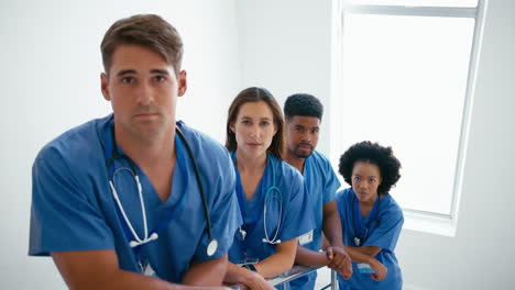 Portrait-Of-Smiling-Multi-Cultural-Medical-Team-Wearing-Scrubs-Standing-On-Stairs-In-Hospital
