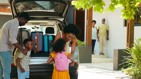 Grandparents-Greeting-Grandchildren-As-Family-Unpack-Car-On-Family-Holiday
