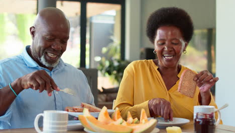 Senior-Couple-At-Home-Enjoying-Breakfast-Around-Table-Together