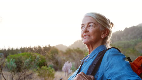 Close-Up-Portrait-Of-Active-Senior-Woman-With-Backpack-Hiking-In-Countryside