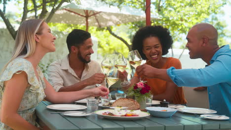 Grupo-De-Amigos-Disfrutando-De-Comida-Y-Vino-Al-Aire-Libre-En-Una-Visita-Al-Restaurante-Vineyard