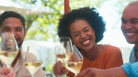 Portrait-Of-Group-Of-Friends-Enjoying-Outdoor-Meal-And-Wine-On-Visit-To-Vineyard-Restaurant