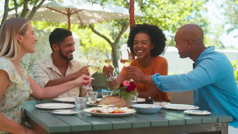 Group-Of-Friends-Enjoying-Outdoor-Meal-And-Wine-On-Visit-To-Vineyard-Restaurant