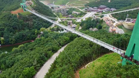 Stunning-aerial-view-of-suspension-glass-bridge-at-Huaxiacheng-theme-park-in-Weihai,-China