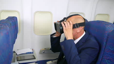 Ein-Geschäftsmann,-Der-In-Der-Kabine-Eines-Passagierflugzeugs-Sitzt-Und-Ein-VR-Virtual-Reality-Headset-Aufsetzt