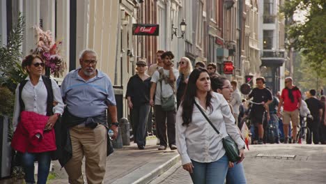 Large-group-of-tourists-walking-on-a-busy-street-in-Amsterdam-city-center
