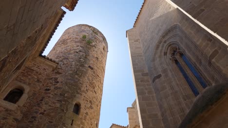 Historic-Torre-de-Carvajal,-Cáceres,-Spain:-stone-tower-in-charming-alley---tilt-down