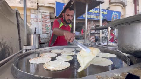 Expert-bread-maker-making-parathas-and-oiling-them-on-a-big-frying-pan---Pakistan-street-food