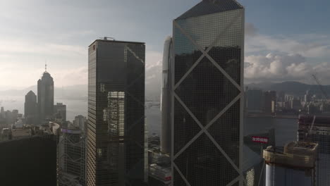 Filmische-Drohnenaufnahme-Des-IFC-Gebäudes-Zwischen-Cheung-Kong-Center-Und-Bank-Of-China-Mit-Dramatischen-Wolken-Im-Hintergrund