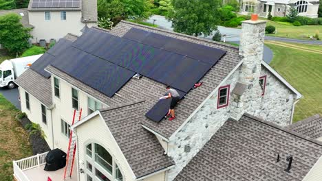 Junger-Männlicher-Arbeiter-Installiert-Solaranlage-Auf-Einem-Geneigten-Schindeldach-In-Einem-Wohngebiet