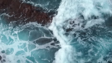 Bird's-eye-view-of-powerful-waves-crashing-on-rocky-coastline,-tracking-shot