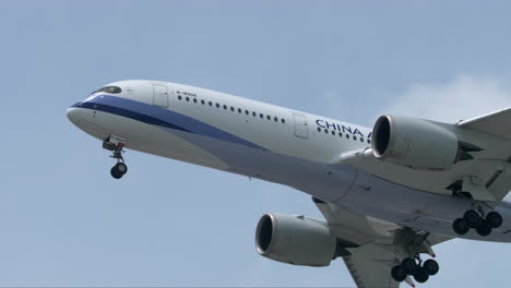 Ein-Airbus-Der-Chinesischen-Fluggesellschaft-Landet-Auf-Dem-Suvarnabhumi-Flughafen-In-Bangkok,-Thailand,-Und-Zeigt-Auch-Flauschige-Wolken-Und-Vorbeifliegende-Vögel