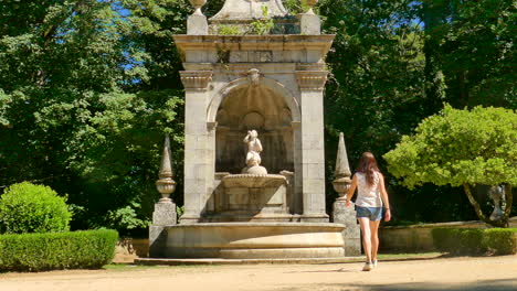 Young-woman-walking-near-the-fountain-in-Notre-Dame-des-Remedes-Lamego,-Portugal