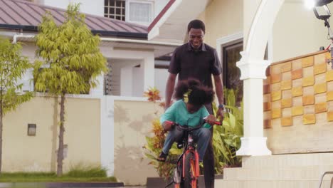 close-up-of-Black-American-father-teaching-his-daughter-how-to-ride-bicycle-at-home