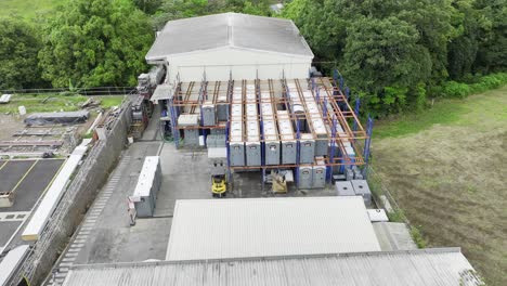 Aerial-drone-shot-:-a-sprawling-warehouse-storing-many-chemical-toilets,-with-forklifts-ready-to-be-used