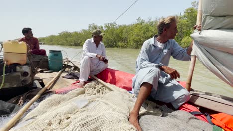 Fishing-boat-with-fishermen-moving-on-the-Arabian-Sea-near-mangrove-forest-in-Sindh-Coast,-Pakistan