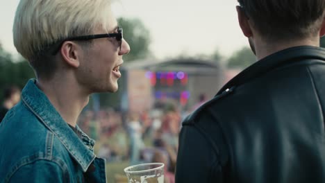 Rear-view-of-two-young-caucasian-men-having-fun-on-music-festival-while-drinking-beer