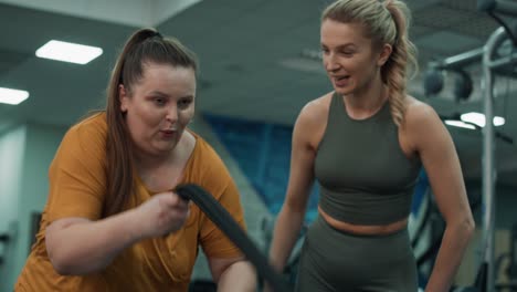 Woman-with-overweight-exercising-with-battle-ropes-and-female-trainer-at-the-gym.