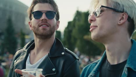 Two-young-caucasian-men-having-fun-on-music-festival-while-drinking-beer.