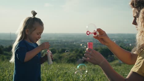 Little-caucasian-girl-with-mom-playing-with-bubbles.