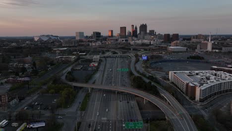 Vista-Aérea-Cinematográfica-De-La-Autopista-Del-Centro-De-Atlanta-Con-Vistas-A-Los-Famosos-Edificios-Del-Horizonte-Al-Fondo-Al-Atardecer,-Tráfico-En-La-Autopista-En-Una-Ciudad-Urbana-Moderna-En-Los-EE.UU.