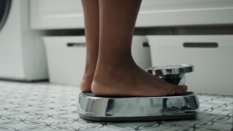 Feet-of-unrecognizable-African-American-woman-stepping-on-the-bathroom-scale.