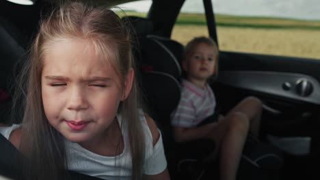 Kaukasisches-Mädchen-Von-8-Jahren,-Das-Während-Einer-Autofahrt-Aus-Dem-Autofenster-Schaut,-Und-Ihre-Schwester-Im-Hintergrund.
