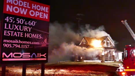 An-establishing-pan-shot-at-the-scene-of-a-residential-house-fire,-the-luxury-home-billowing-smoke-as-firefighters-attempt-to-extinguish-the-blaze-at-night
