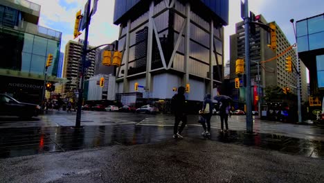 Yonge-Bloor-North-East-Corner-looking-at-diagonal-crossing-pedestrian-scramble-raining-puddles-reflecting-cars-people-on-the-go-white-city-morphing-into-modern-architectural-beauty