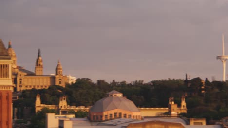 Famous-Olympic-Ring,-Camera-panning-left-to-Torres-Venecianes-twin-towers-and-National-Palace-in-the-background-at-Placa-d'Espanya-square,-Barcelona,-Spain