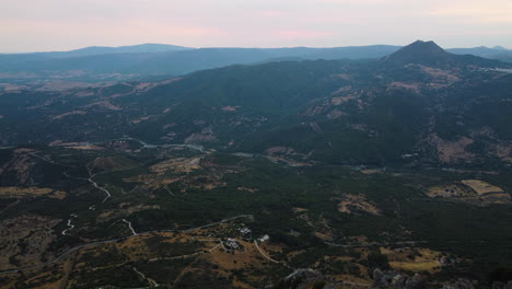 Un-Dron-Se-Eleva-Sobre-Los-Picos-De-Piedra-De-Una-Montaña,-Revelando-Un-Amplio-Valle
