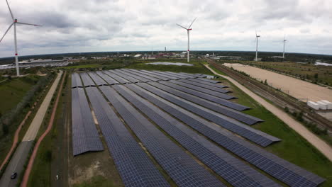 Wind-turbines-and-solar-panels-generate-electricity-in-rural-fields-of-Belgium,-aerial-view