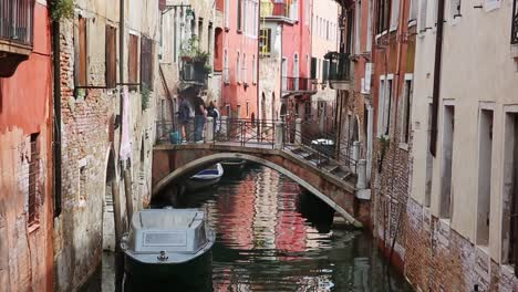 Tourist-walk-on-traditional-bridge-over-canal-in-Venice,-Italy