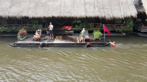 Family-enjoys-their-dock-at-floating-hotel-along-the-River-Kwai-in-Kanchanaburi,-Thailand