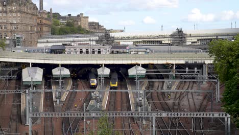 Yellow-Train-Leaving-Edinburgh-Waverly-Station-In-Scotland,-Wide-Camera-View