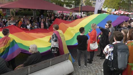 Multitud-De-Jóvenes-Gays-Queer-Ondeando-Juntos-Una-Enorme-Bandera-Del-Arco-Iris-En-El-Desfile-Del-Orgullo-Gay-En-La-Ciudad-De-Kufstein.