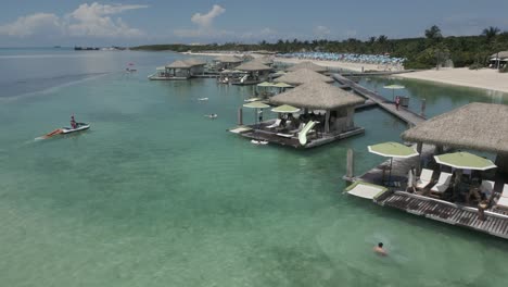 Tourists-enjoy-relaxing-in-grass-thatch-roof-huts-in-shallow-Coco-Cay