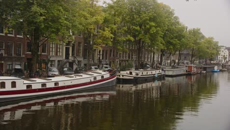Pan-over-houseboats-on-canal-in-Amsterdam,-the-Netherlands