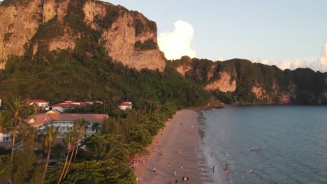 Ascending-aerial-shot-of-Ao-Nang-beach-cliff-faces-at-sunset