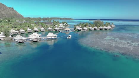 Barco-Navegando-En-La-Laguna-Azul-A-Lo-Largo-De-Las-Villas-Acuáticas-Del-Hotel-En-Verano-En-Moorea,-Polinesia-Francesa