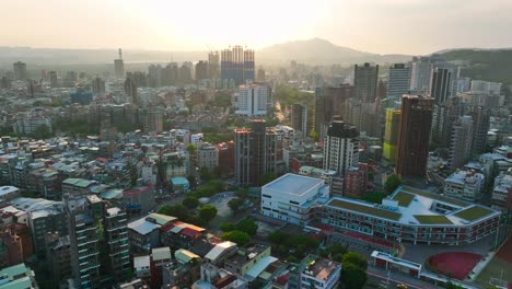 Sobrevuelo-Aéreo-Del-Rico-Distrito-De-Tienmu-En-La-Ciudad-De-Taipei-Con-Puesta-De-Sol-Dorada-En-El-Fondo,-Taiwán---Drone-Estableciendo-Vuelo