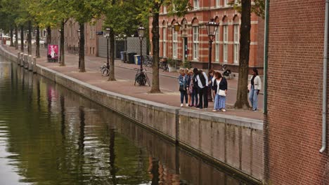 People-standing-on-Quay-and-looking-onto-canal-in-Amsterdam-city-center