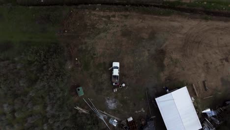 Cinematic-aerial-drone-top-shot-of-farmer-putting-things-in-pick-up-truck
