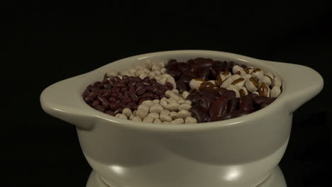 Bowl-of-dry-beans-revolves-isolated-on-black-background,-copy-space