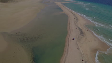 Sotavento-Beach,-Fuerteventura:-wonderful-aerial-view-traveling-in-to-the-fantastic-beach-and-people-enjoying-the-day