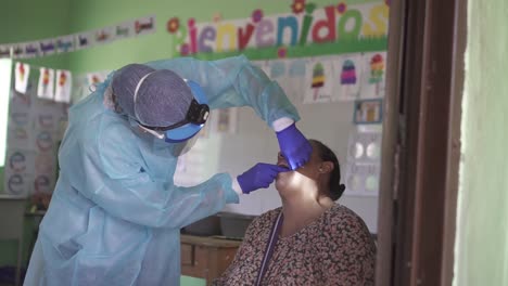 Female-dentist-cleans-the-teeth-of-an-adult-woman-with-dental-floss-during-a-medical-brigade-in-an-improvised-clinic,-in-a-poor-community-school