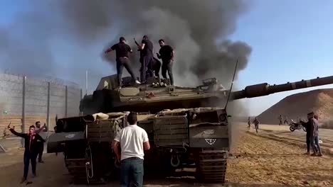 Palästinenser-Auf-Zerstörtem-Israelischen-Militärpanzer-Am-Zaun-Des-Gazastreifens,-Al-Aqsa-Überschwemmungseinsatz-Der-Hamas,-10.07.2023