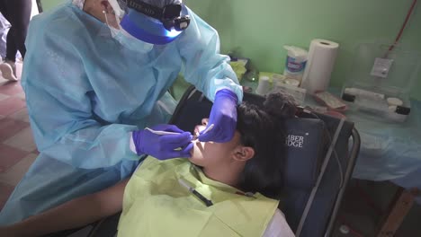 Una-Dentista-Trata-A-Una-Niña-Durante-Una-Brigada-Médica-En-Una-Clínica-Improvisada,-En-Una-Escuela-De-Una-Comunidad-Pobre.