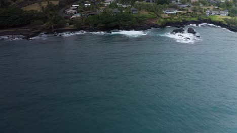 Aerial-low-tilting-up-shot-of-Hana-Bay-and-the-small-Hawaiian-village-of-Hana-Town-on-the-slopes-of-Haleakala-in-Maui,-Hawai'i