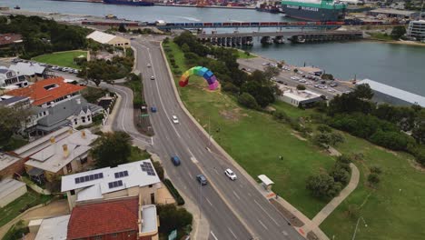 Aerial-drone-forward-moving-shot-over-road-alongside-Port-Beach,-North-Fremantle,-West-Australia-on-a-cloudy-day